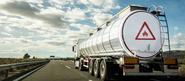 A dangerous goods truck carrying flammable liquids drives along the highway on a sunny day.