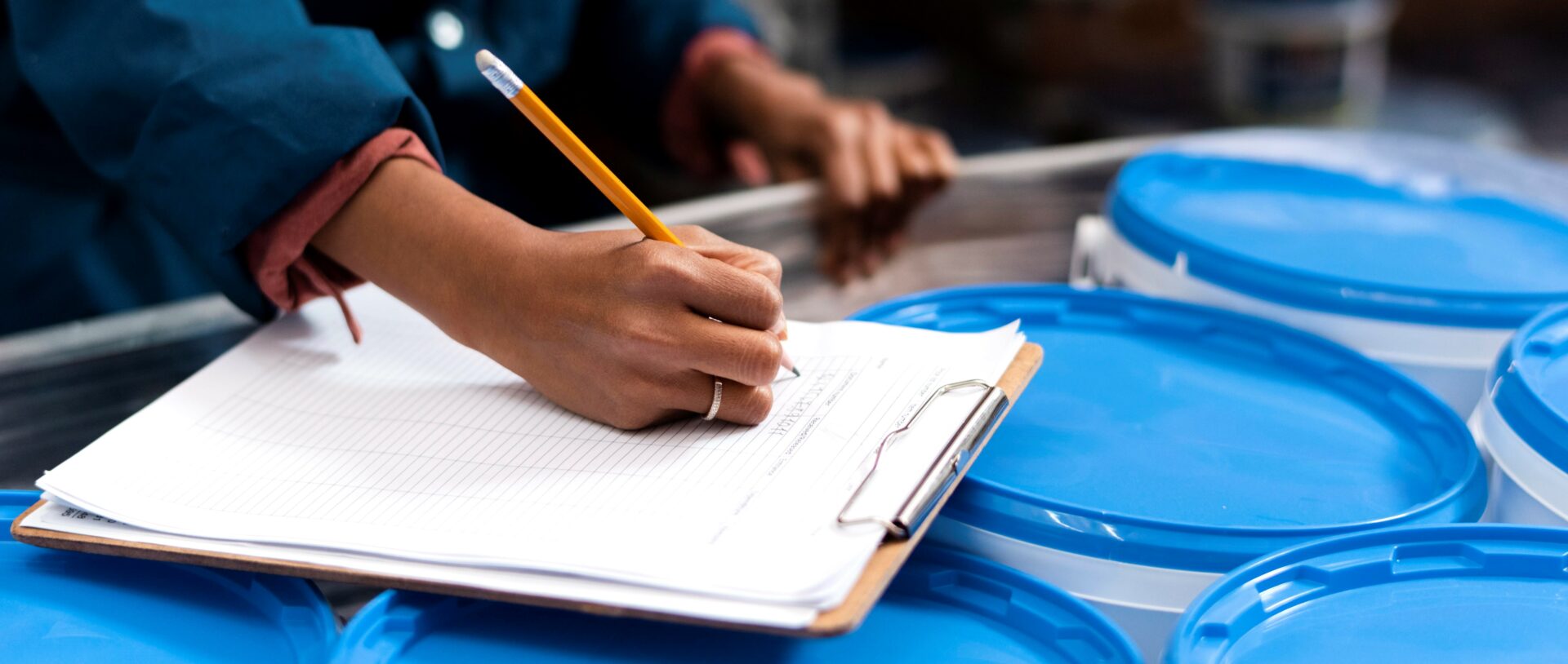 Woman working in dangerous goods storage facility takes notes on corrosive substances.