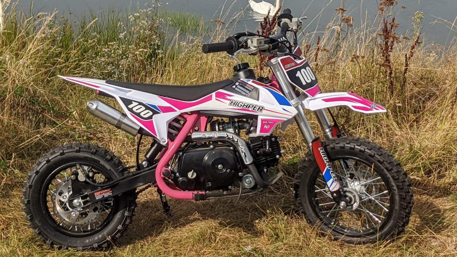 A pink pitbike standing outside